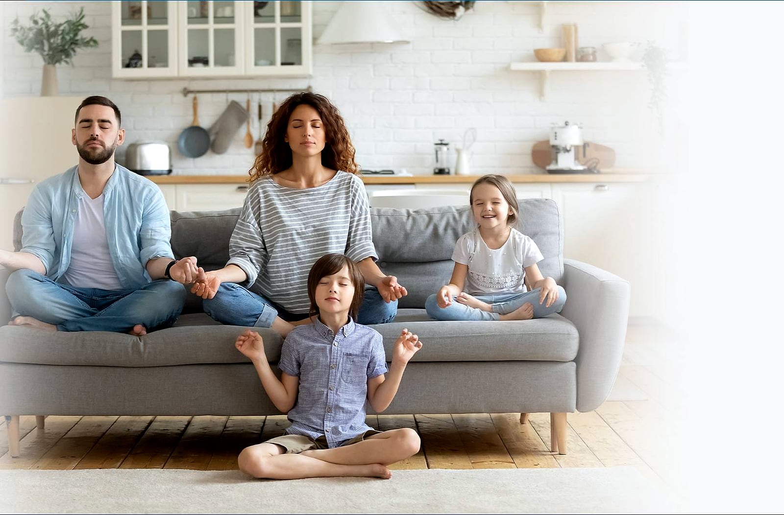 A family of four sitting cross-legged and relaxed in a bright living room