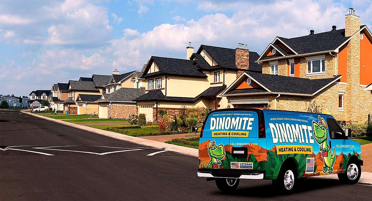 A Dinomite Heating & Cooling service van parked on a residential street lined with houses